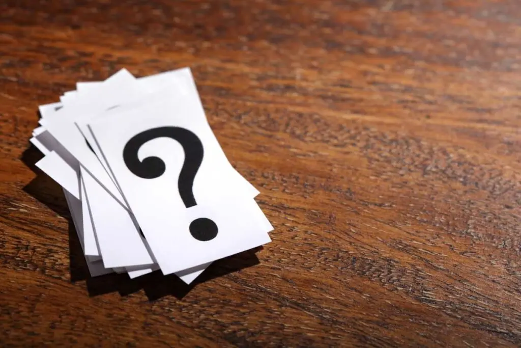 A stack of papers with question marks on a table