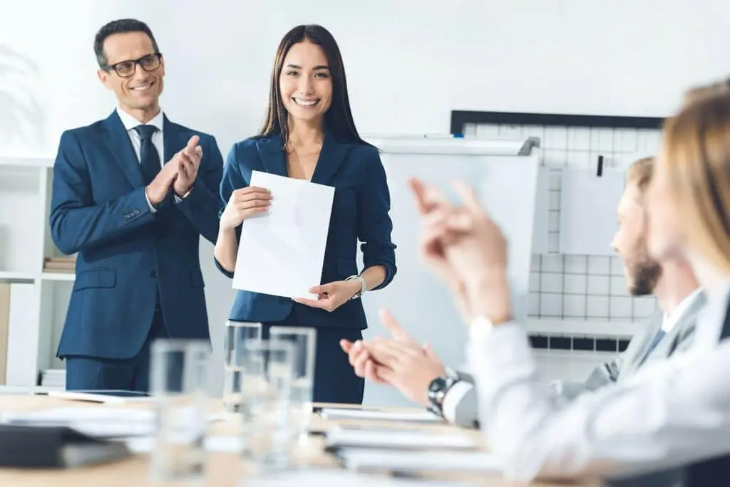Colleagues applauding a woman at work