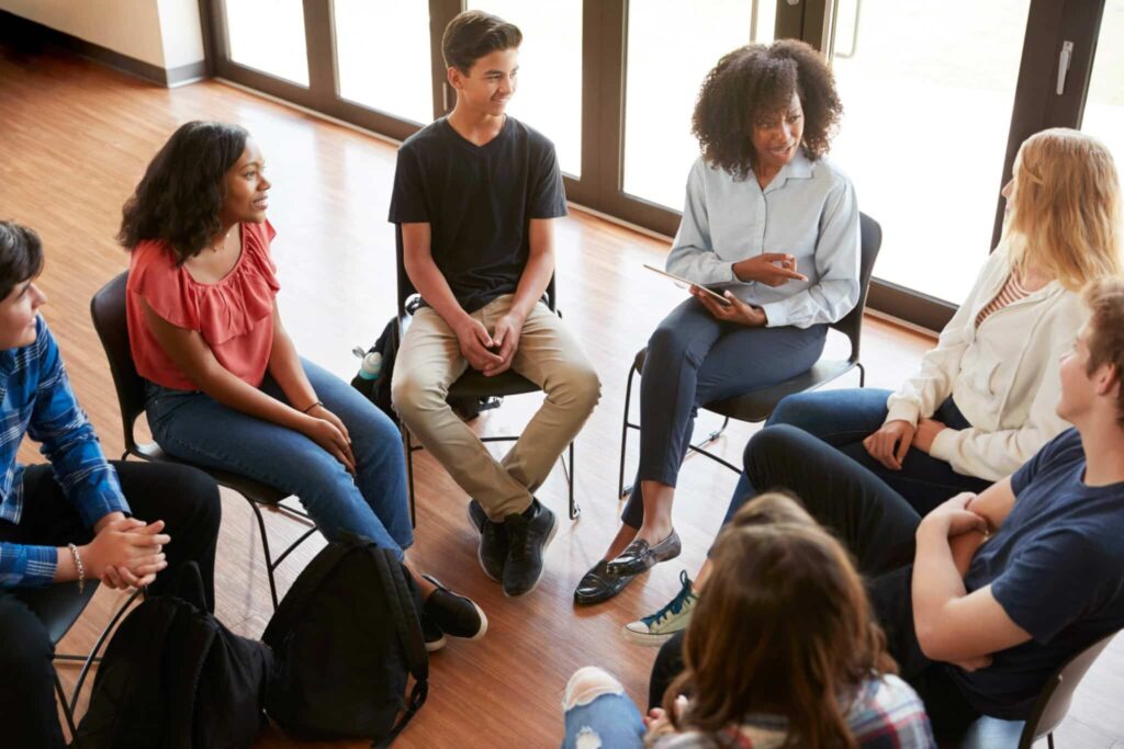 A group of young people sitting in a circle and engaging in lively and enjoyable conversation