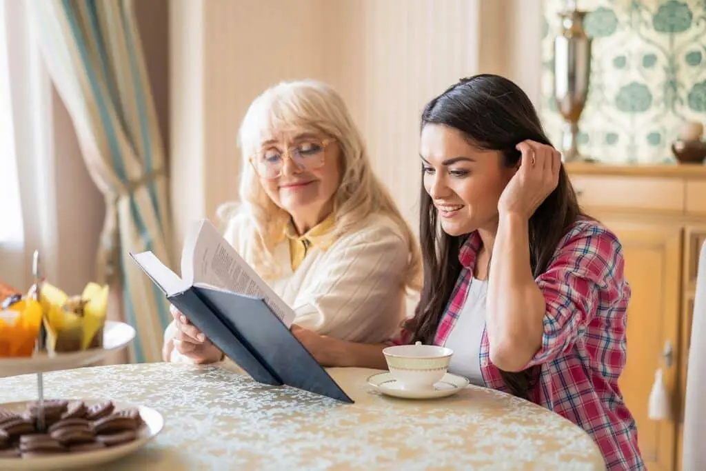 A grandmother and a girl reading a book at a table