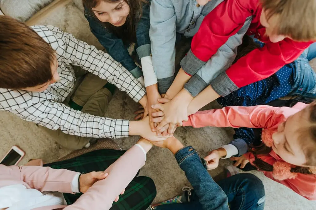 Children sitting in a circle with their hands stacked together